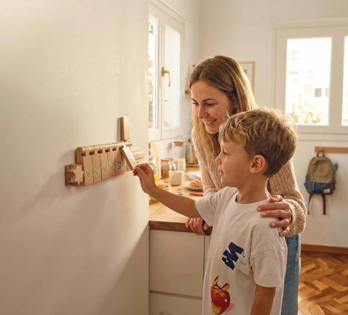 Parent and child using a wall-mounted Flipzy routine board