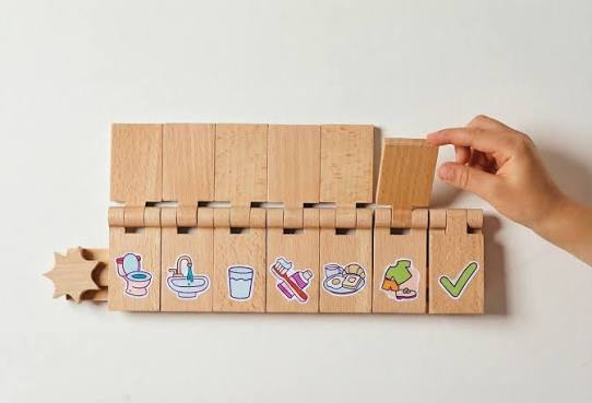 Flipzy board with a hand flipping one wooden task tile